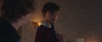 Movie still from “Better Watch Out” (2016), directed by Chris Peckover – A young boy holding a gun while standing in a room; Close Up shot, Over the shoulder angle