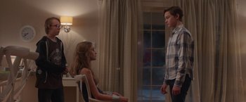 Movie still from “Better Watch Out” (2016), directed by Chris Peckover – A girl sitting on a chair next to a boy; Medium shot, Low angle