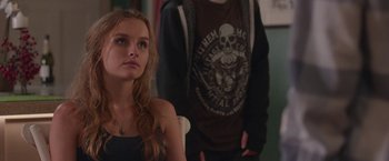 Movie still from “Better Watch Out” (2016), directed by Chris Peckover – A woman sitting in front of a man wearing a shirt with a skull on it; Close Up shot, Over the shoulder angle
