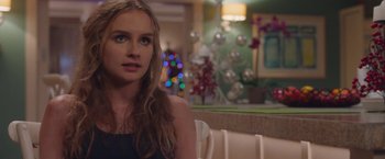 Movie still from “Better Watch Out” (2016), directed by Chris Peckover – A beautiful young lady sitting at a table in front of christmas decorations; Close Up shot, Over the shoulder angle