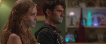 Movie still from “Better Watch Out” (2016), directed by Chris Peckover – A man and a woman with their mouths taped shut; Close Up shot, Over the shoulder angle