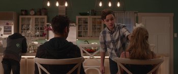 Movie still from “Better Watch Out” (2016), directed by Chris Peckover – Two young men sitting at a kitchen table talking to each other; Medium shot, Over the shoulder angle