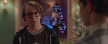 Movie still from “Better Watch Out” (2016), directed by Chris Peckover – A young man wearing glasses in front of a christmas tree; Close Up shot, Over the shoulder angle