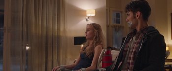 Movie still from “Better Watch Out” (2016), directed by Chris Peckover – A woman sitting in a chair in front of a television; Medium shot, Low angle