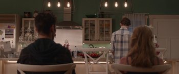 Movie still from “Better Watch Out” (2016), directed by Chris Peckover – Two people are sitting in a kitchen with a stove and a counter; Medium shot, Over the shoulder angle