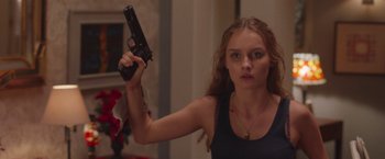 Movie still from “Better Watch Out” (2016), directed by Chris Peckover – A woman holding a gun up to her face; Medium shot, Low angle