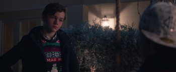Movie still from “Better Watch Out” (2016), directed by Chris Peckover – A young boy wearing a christmas sweater standing in front of a tree; Close Up shot, Over the shoulder angle