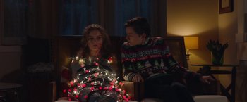 Movie still from “Better Watch Out” (2016), directed by Chris Peckover – A man and a woman sitting next to each other with christmas lights; Medium shot, Low angle