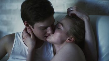 A couple of people laying in a bed kissing each other