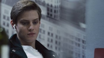A young man in a white shirt and black jacket looking to his left