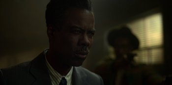 Movie still from “Fargo” (2014), created by Noah Hawley – A man in a suit and tie looking at the camera; Close Up shot, Over the shoulder angle