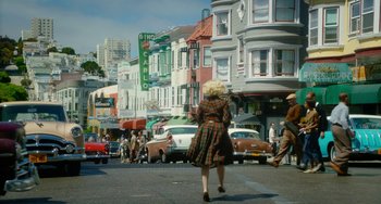 Movie still from “Big Eyes” (2014), directed by Tim Burton – A woman walking down the street in a plaid dress; Wide shot, High angle