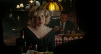 Movie still from “Big Eyes” (2014), directed by Tim Burton – A woman sitting at a table with a glass of red wine; Medium shot, Over the shoulder angle