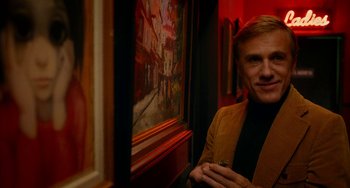 Movie still from “Big Eyes” (2014), directed by Tim Burton – A man standing in front of a painting in a room; Medium shot, Low angle