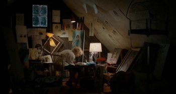 Movie still from “Big Eyes” (2014), directed by Tim Burton – A woman sitting at a table in a room filled with paintings; Wide shot, Overhead angle