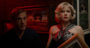 Movie still from “Big Eyes” (2014), directed by Tim Burton – A man and a woman standing next to each other in a room; Medium shot, Low angle