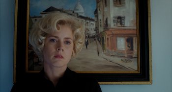 Movie still from “Big Eyes” (2014), directed by Tim Burton – A woman with blonde curly hair standing in front of a painting; Close Up shot, Low angle