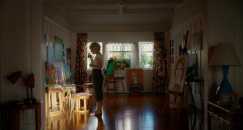 Movie still from “Big Eyes” (2014), directed by Tim Burton – A woman standing in front of a painting in a room; Wide shot, Low angle