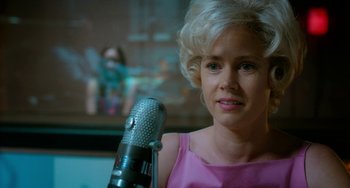 Movie still from “Big Eyes” (2014), directed by Tim Burton – A woman in a pink top is holding a microphone; Close Up shot, Over the shoulder angle
