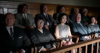 Movie still from “Big Eyes” (2014), directed by Tim Burton – A group of people sitting in a row in front of a wooden wall; Medium shot, High angle