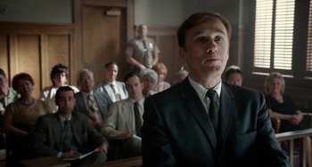 Movie still from “Big Eyes” (2014), directed by Tim Burton – A man in a suit and tie in front of a group of people; Medium shot, Low angle