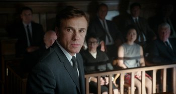 Movie still from “Big Eyes” (2014), directed by Tim Burton – A man wearing a suit and tie in front of a group of people; Medium shot, Low angle