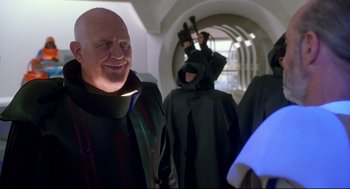 Movie still from “Bill & Ted's Bogus Journey” (1991), directed by Peter Hewitt – A man with a beard is smiling in front of other men; Medium shot, Over the shoulder angle