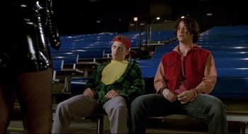 Movie still from “Bill & Ted's Bogus Journey” (1991), directed by Peter Hewitt – Two men sitting in a stadium with one wearing a red jacket; Medium shot, Low angle