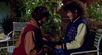 Movie still from “Bill & Ted's Bogus Journey” (1991), directed by Peter Hewitt – Two young people are holding hands in front of some plants; Medium shot, Over the shoulder angle