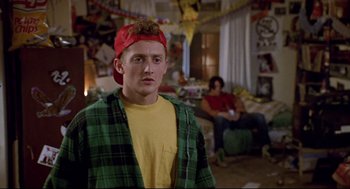 Movie still from “Bill & Ted's Bogus Journey” (1991), directed by Peter Hewitt – A young man wearing a red hat in a living room; Medium shot, Over the shoulder angle