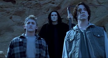 Movie still from “Bill & Ted's Bogus Journey” (1991), directed by Peter Hewitt – A group of young men standing next to each other in front of a cave; Medium shot, Low angle