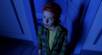 Movie still from “Bill & Ted's Bogus Journey” (1991), directed by Peter Hewitt – A young boy standing in a doorway wearing a red hat; Medium shot, High angle