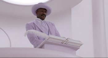 A man wearing a purple suit and a white hat