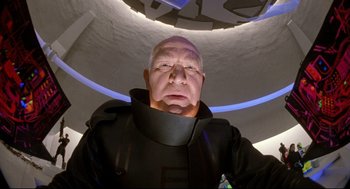 Movie still from “Bill & Ted's Bogus Journey” (1991), directed by Peter Hewitt – An older man wearing a black suit and a neck brace; Close Up shot, Low angle