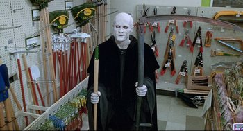Movie still from “Bill & Ted's Bogus Journey” (1991), directed by Peter Hewitt – A man dressed as the white witch holding a scythe; Medium shot, Low angle