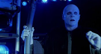 Movie still from “Bill & Ted's Bogus Journey” (1991), directed by Peter Hewitt – A man with a bald head is holding a microphone; Medium shot, Low angle