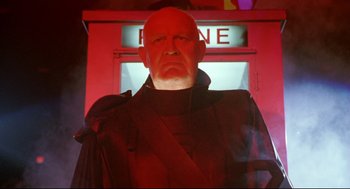 Movie still from “Bill & Ted's Bogus Journey” (1991), directed by Peter Hewitt – An old man in a black jacket standing in front of a red sign; Medium shot, Low angle