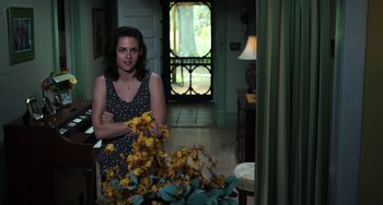 Movie still from “Billy Lynn's Long Halftime Walk” (2016), directed by Ang Lee – A woman standing in front of a vase of yellow flowers; Medium shot, Over the shoulder angle
