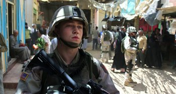 Movie still from “Billy Lynn's Long Halftime Walk” (2016), directed by Ang Lee – A man in a military uniform holding a rifle; Medium shot, Over the shoulder angle
