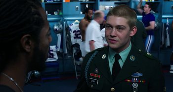 Movie still from “Billy Lynn's Long Halftime Walk” (2016), directed by Ang Lee – A man in a military uniform in front of a group of people; Medium shot, Over the shoulder angle