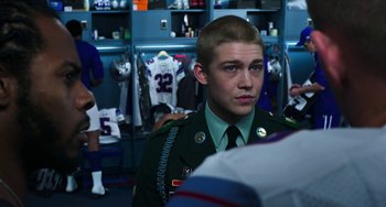 Movie still from “Billy Lynn's Long Halftime Walk” (2016), directed by Ang Lee – A young man in a military uniform in a locker room; Medium shot, Over the shoulder angle