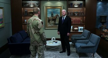 Movie still from “Billy Lynn's Long Halftime Walk” (2016), directed by Ang Lee – A man in a suit stands next to another man in a uniform; Wide shot, Over the shoulder angle