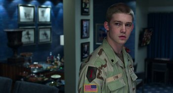 Movie still from “Billy Lynn's Long Halftime Walk” (2016), directed by Ang Lee – A man in a military uniform standing in a room; Medium shot, Over the shoulder angle
