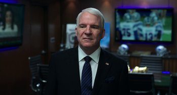 Movie still from “Billy Lynn's Long Halftime Walk” (2016), directed by Ang Lee – A man in a suit and tie in a room; Medium shot, Over the shoulder angle