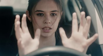 A woman is driving a car with her hands on the steering wheel