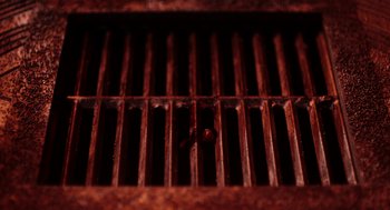 Movie still from “Bit” (2019), directed by Brad Michael Elmore – View of the grill grate of an outdoor grill; Extreme Close Up shot, Overhead angle