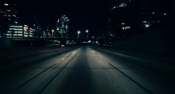 Movie still from “Bit” (2019), directed by Brad Michael Elmore – A night time view of an empty freeway; Extreme Wide shot, High angle