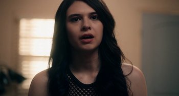Movie still from “Bit” (2019), directed by Brad Michael Elmore – A woman with long black hair wearing fishnet top; Close Up shot, Over the shoulder angle