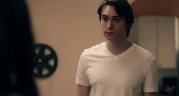 A man in a white t - shirt standing in front of a wall