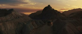 Movie still from “Black Adam” (2022), directed by Jaume Collet-Serra – A van driving down a dirt road near a mountain; Extreme Wide shot, High angle